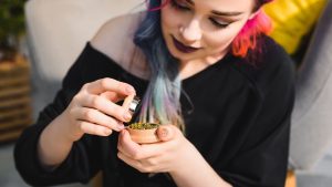 A woman holding and looking into her grinder