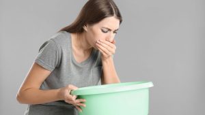 A woman with a basin suffering from nausea. symptom of cannabinoid hyperemesis syndrome
