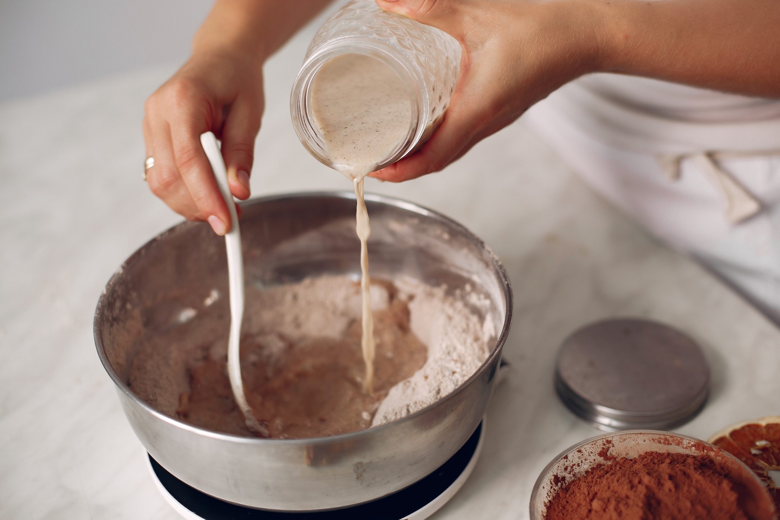 Woman pours milk into a bowl. Confectioner mixes the ingredients. Lady is preparing dessert.