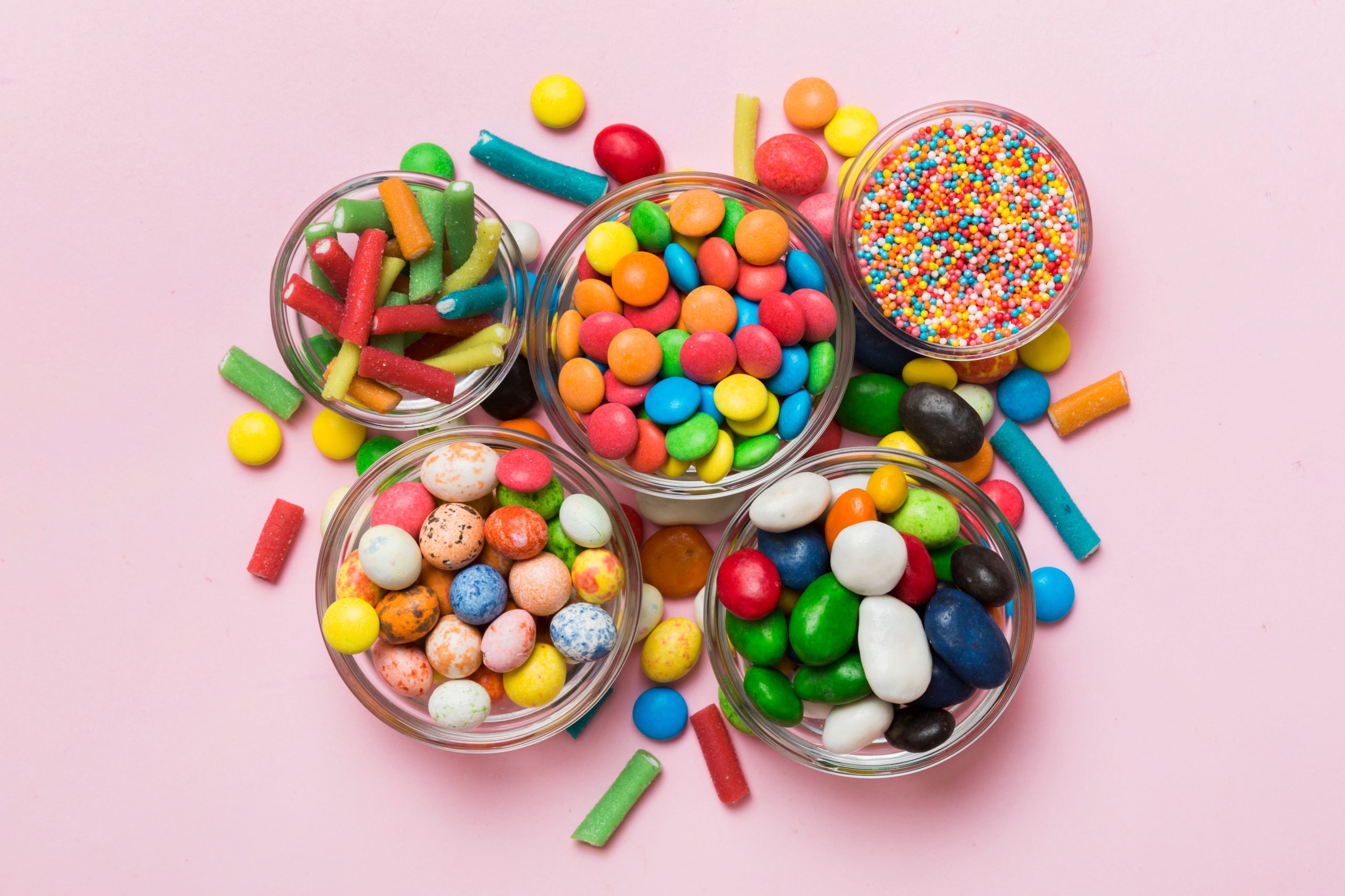 different colored round candy in bowl and jars. Top view of large variety sweets and candies with copy space.